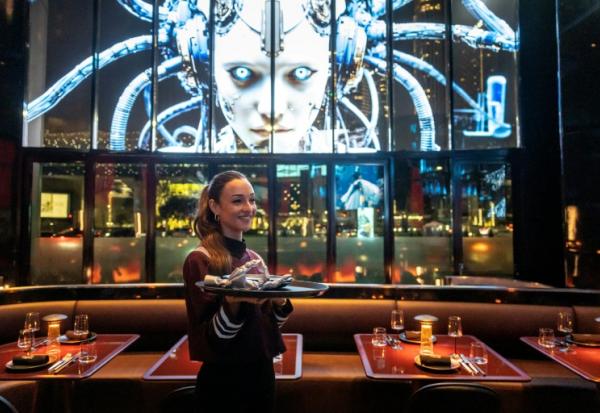 Une serveuse s'apprêtant à servir un plat au Woohoo, un restaurant qui se prévaut d'être piloté par le premier "chef IA" au monde, pose pour une photo, à Dubaï, le 12 novembre 2025