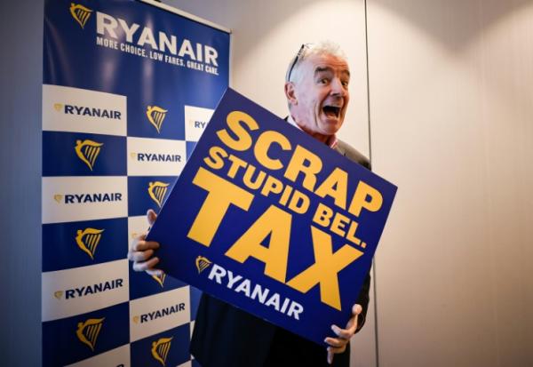Michael O'Leary, PDG de la compagnie aérienne Ryanair pose avec une pancarte reprochant à la Belgique une série de taxes "stupides", lors d'une conférence de presse à Bruxelles le 14 janvier 2026