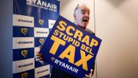 Michael O'Leary, PDG de la compagnie aérienne Ryanair pose avec une pancarte reprochant à la Belgique une série de taxes "stupides", lors d'une conférence de presse à Bruxelles le 14 janvier 2026