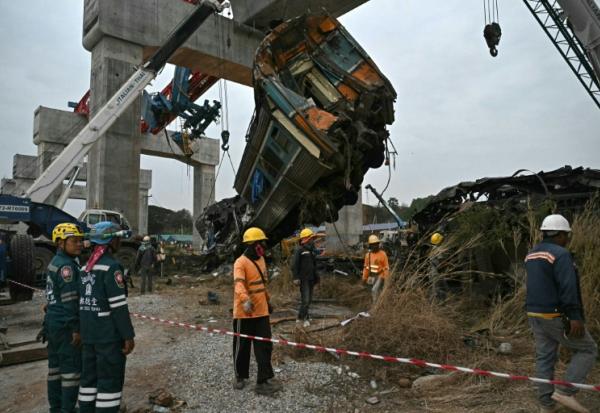 Des secouristes sur le site du déraillement d'un train provoqué par l'effondrement d'une grue de chantier dans la province de Nakhon Ratchasima, en Thaïlande, le 14 janvier 2026