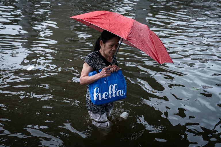 Une femme se fraye un chemin dans une rue inondée de Bangkok, où l'état de catastrophe naturelle a été déclaré après des pluies diluviennes qui ont inondé habitations, commerces et axes de circulation, le 27 septembre 2026