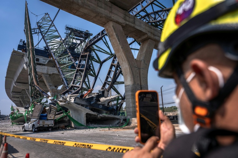 Un secouriste prend des photos là où une grue de chantier s'est effondrée sur une autoroute à Samut Sakhon, dans la banlieue de Bangkok, le 15 janvier 2026