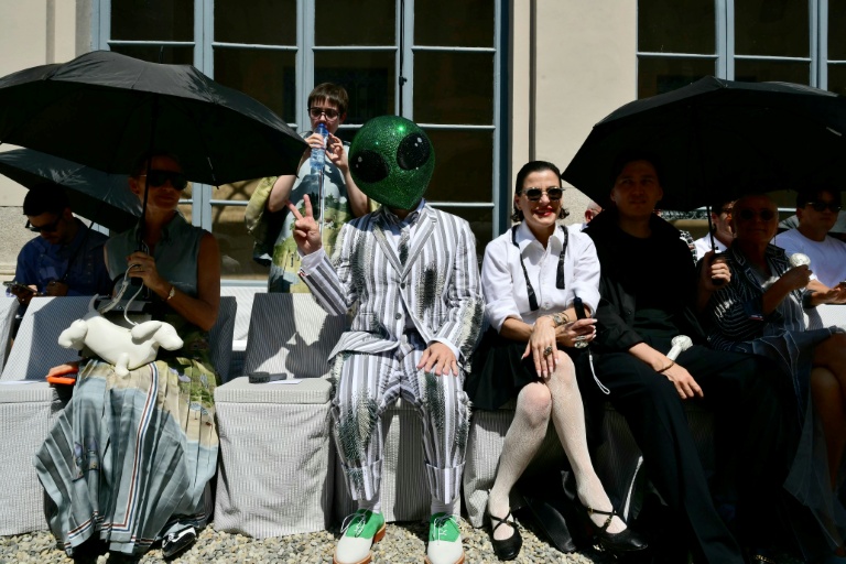 Un invité portant un masque d'extraterrestre assiste au défilé de la collection Thom Browne lors de la Fashion Week Homme Printemps/Été 2027 de Milan, à Milan, le 22 juin 2026