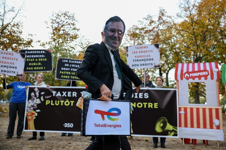 Un militant écologiste porte un masque à l’effigie de Patrick Pouyanné, PDG de TotalEnergies, lors d’une manifestation contre l’austérité gouvernementale et les coupes budgétaires, le 29 octobre 2026 à Paris