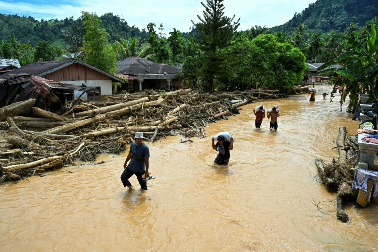 Des habitants pataugent dans les eaux après les inondations soudaines survenues dans le village de Tukka, à Tapanuli central, dans la province de Sumatra du Nord, le 2 décembre 2025