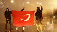 Des manifestants tiennent le drapeau turc lors de heurts avec la police, le 23mars 2025 à Ankara