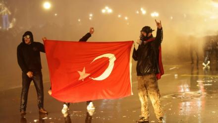 Des manifestants tiennent le drapeau turc lors de heurts avec la police, le 23mars 2025 à Ankara