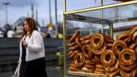 Une femme passe à côté d'un vendeur de simits, petits pains ronds turcs en forme d'anneau, le 27 décembre 2025 à Istanbul