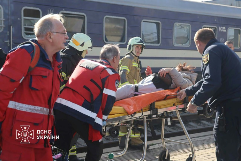 Photo diffusée par le Service ukrainien des situations d'urgence le 29 octobre 2026 montrant des secouristes ukrainiens transportant sur une civière une personne blessée après une attaque aérienne contre la gare de Dnipro, en Ukraine