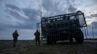 Des soldats ukrainiens devant un véhicule militaire blindé entouré d'une cage de protection contre les attaques de drones, sur une route près d'Oleksandrivka, le 6 octobre 2025