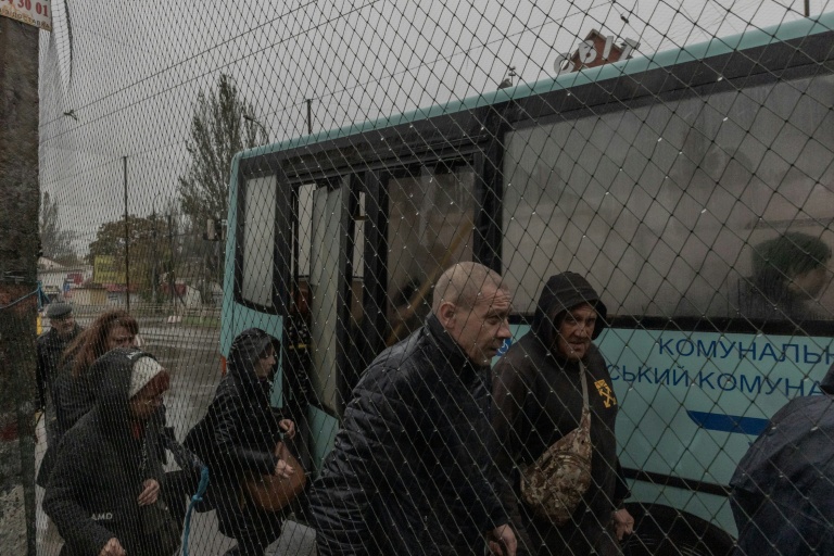 Des passagers à une station de bus où des filets antidrones ont été disposés le long de la route, le 30 octobre 2026 à Kherson, dans le sud de l'Ukraine 

