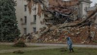 Un employé municipal ramasse de l'herbe coupée près d'un bâtiment administratif en partie détruit par une frappe russe, le 30 octobre 2026 à Kherson, dans le sud de l'Ukraine 