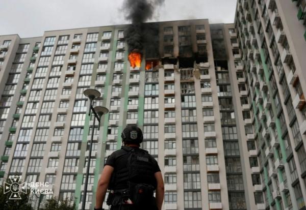 Photo prise et publiée par les services de secours ukrainiens le 1er septembre 2026, montrant un policier devant un immeuble d'habitation en feu à Kiev, après une frappe russe