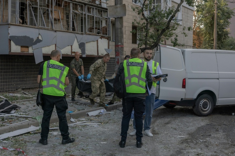 Le corps d'une victime est transporté dans un van à côté d'un immeuble résidentiel endommagé à la suite d'une frappe russe à Kiev, le 20 août 2026
