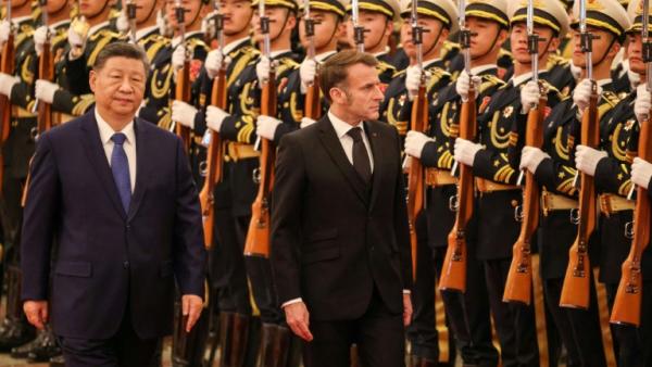 Le président chinois Xi Jinping (à gauche) et le président français Emmanuel Macron (à droite) passent en revue la garde d'honneur lors d'une cérémonie de bienvenue au Palais du Peuple à Pékin, le 4 décembre 2025