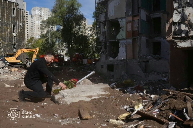 Photo prise et diffusée par les services d'urgence ukrainiens, le 15 mai 2026, montrant le président ukrainien Volodymyr Zelensky (c) rencontrant des secouristes ukrainiens sur le site d'une attaque aérienne à Kiev