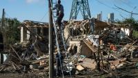 Des électriciens ukrainiens réparent le réseau électrique devant une maison privée détruite où un adolescent de 14 ans a été tué lors d'une attaque aérienne à Vyshgorod, dans la région de Kiev, le 30 septembre 2026