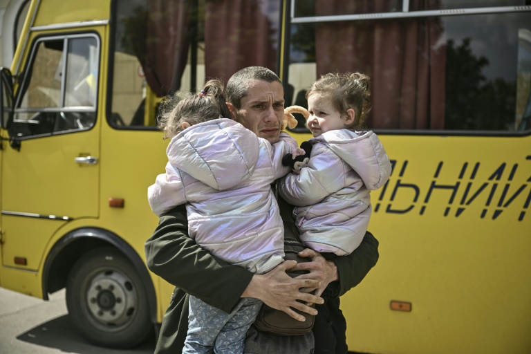 32-year-old Dmytro Mosur, who lost his wife in a bombardment near Severodonetsk, carries a two-year-old twin girl on May 20, 2022, while waiting to be evacuated from Lysychank.