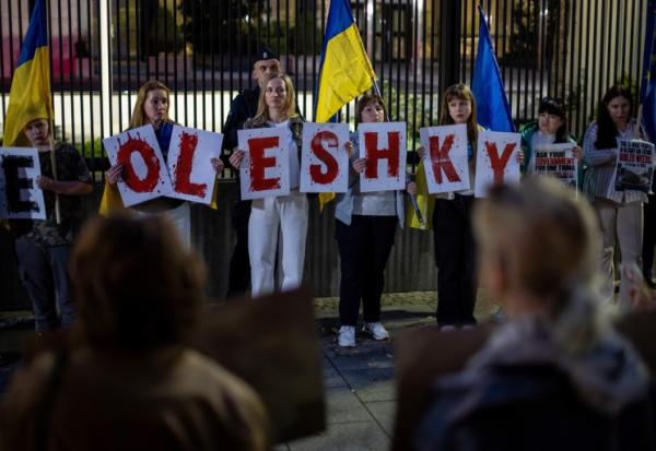 Des membres de la diaspora ukrainienne tiennent des pancartes formant le nom Oleshky (Olechky) devant l'ambassade américaine à Varsovie, le 6 octobre 2026, en Pologne