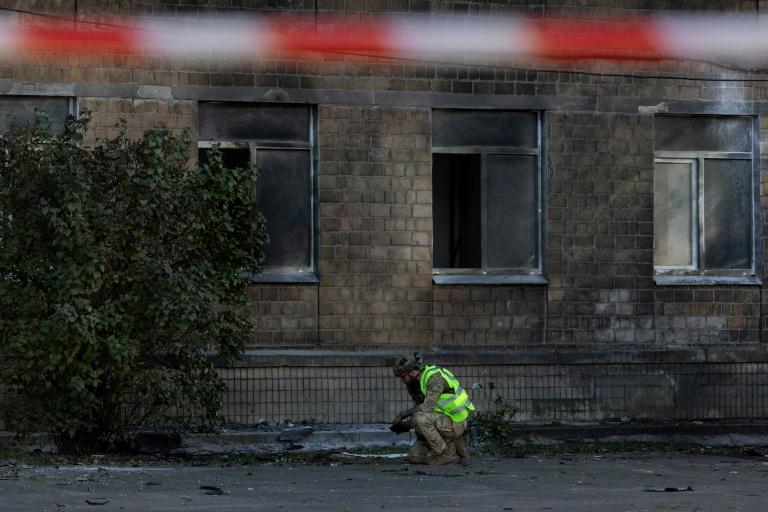 Un policier ukrainien inspecte des débris près d'un bâtiment endommagé par une frappe de drone russe à Kiev, le 1er octobre 2026