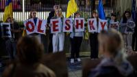 Des membres de la diaspora ukrainienne tiennent des pancartes formant le nom "Oleshky" (Olechky) devant l'ambassade américaine à Varsovie, le 6 octobre 2026
