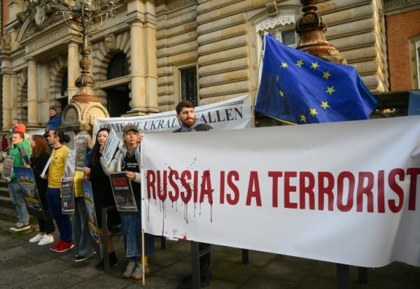 Des manifestants protestent avec des banderoles "la Russie est un terroriste" devant le tribunal où est jugé un ancien officien ukrainien à Hambourg (nord de l'Allemagne), le 14 octobre 2026