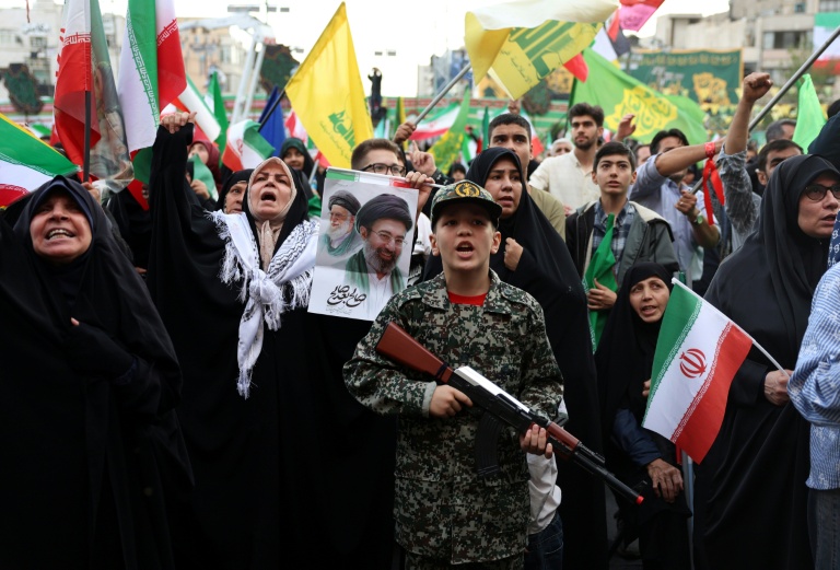 Un jeune Iranien en uniforme militaire brandit un fusil factice lors d'un rassemblement des partisans du pouvoir, le 29 avril 2029 à Téhéran