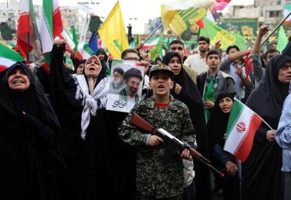 Un jeune Iranien en uniforme militaire brandit un fusil factice lors d'un rassemblement des partisans du pouvoir, le 29 avril 2029 à Téhéran