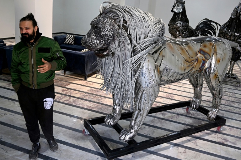Le sculpteur Ehtisham Jadoon à côté de sa création, un lion à la crinière d'acier torsadé réalisé à partir de ferraille, dans son atelier situé à la périphérie d'Islamabad, le 29 décembre 2025 au Pakistan