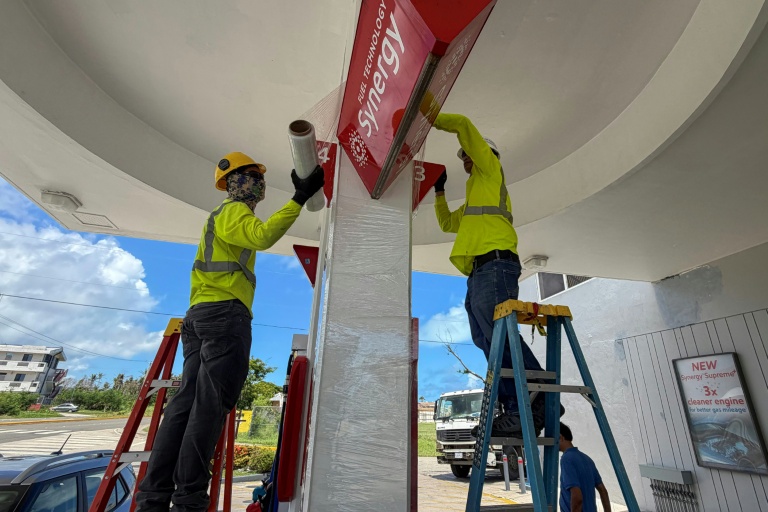 Des ouvriers consolident les panneaux d'une station service avant l'arrivée d'un 