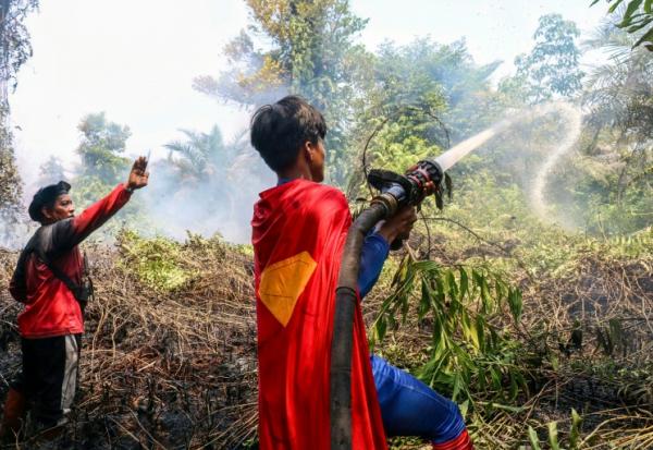 'adolescent indonésien Rudiansyah porte un costume de "Superman" en combattant un incendie, à Palangkaraya, dans le Kalimantan central, le 17 août 2026