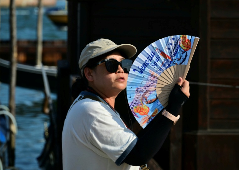 Une touriste utilise un éventail pour se rafraîchir, place Saint-Marc, à Venise, lors d'un épisode de canicule en Europe, le 26 juin 2026