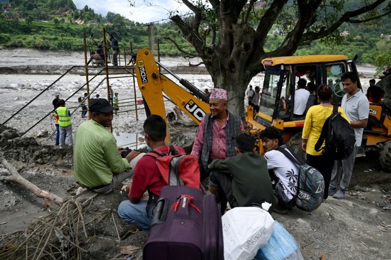 Des habitants regroupés près de la rivière Trishuli tandis que des ouvriers installent une tyrolienne au dessus du cours d'eau à Bidur au Népal le 2 septembre 2026