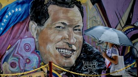 Une femme se protégeant du soleil avec un parapluie arrive au mausolée de l'ancien président vénézuélien Hugo Chavez à Caracas, le 5 mars 2026