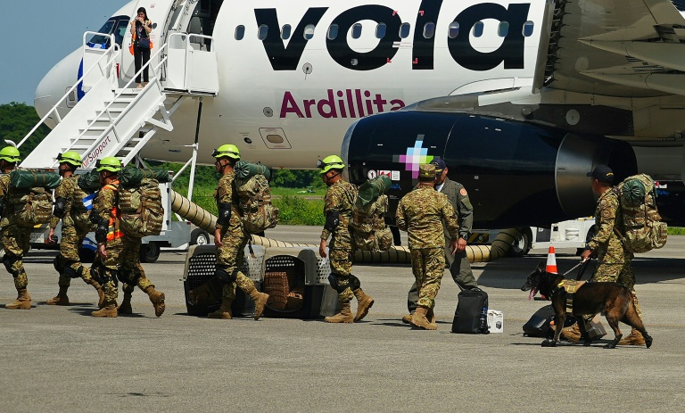 Des militaires salvadoriens accompagnés de chiens renifleurs se préparent à embarquer à bord d’un avion à destination du Venezuela, sur la base aérienne de Comalapa à San Luis Talpa, au Salvador, le 25 juin 2026