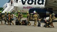 Des militaires salvadoriens accompagnés de chiens renifleurs se préparent à embarquer à bord d’un avion à destination du Venezuela, sur la base aérienne de Comalapa à San Luis Talpa, au Salvador, le 25 juin 2026