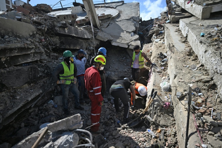 Des secouristes et bénévoles recherchent des survivants dans les déocombres de bâtiments effondrés à Caraballeda, dans l'Etat de La Guaira, le 1er juillet 2026 au Venezuela