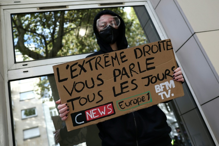 Un manifestant masqué tient une pancarte contre les chaînes de télévision CNews et BFMTV et la station de radio Europe 1 lors d'une manifestation contre la vie chère à Lille, le 17 octobre 2026