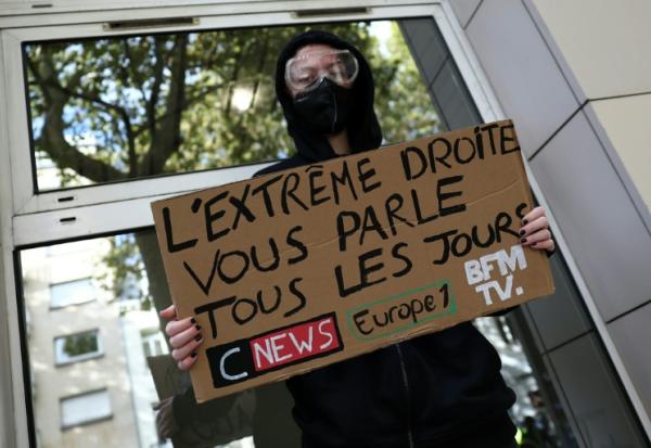 Un manifestant masqué tient une pancarte contre les chaînes de télévision CNews et BFMTV et la station de radio Europe 1 lors d'une manifestation contre la vie chère à Lille, le 17 octobre 2026