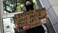 Un manifestant masqué tient une pancarte contre les chaînes de télévision CNews et BFMTV et la station de radio Europe 1 lors d'une manifestation contre la vie chère à Lille, le 17 octobre 2026