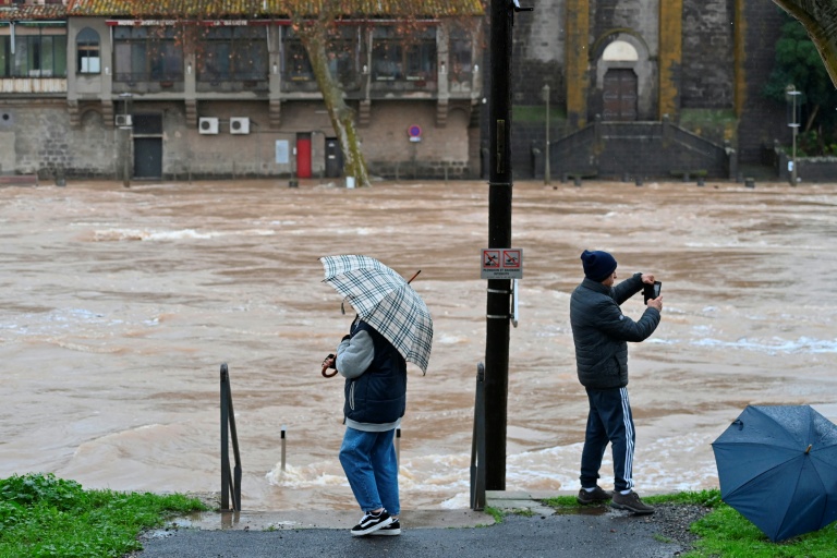 Des passants dans une rue inondée à Agde après un débordement de l'Hérault provoqué par des fortes pluies, le 23 décembre 2025 dans l'Hérault