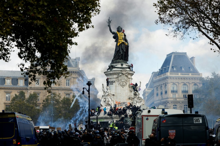 De la fumée enveloppe la Statue de la République, recouverte d'une banderole jaune, lors d'une manifestation contre la vie chère, place de la République à Paris, le 17 octobre 2026