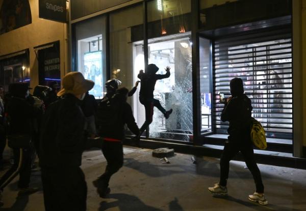 Des personnes s'attaquent à la vitrine d'un magasin à Paris le 18 octobre 2026, au lendemain d'une journée de manifestations marquée par des violences