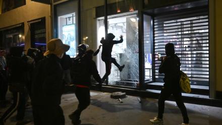 Des personnes s'attaquent à la vitrine d'un magasin à Paris le 18 octobre 2026, au lendemain d'une journée de manifestations marquée par des violences