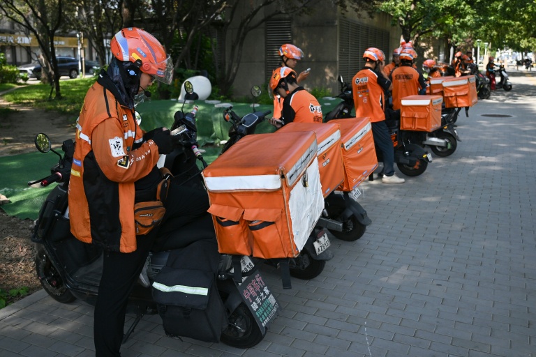 Des livreurs de repas attendent des commandes au bord d'une rue à Pékin, le 2 septembre 2026