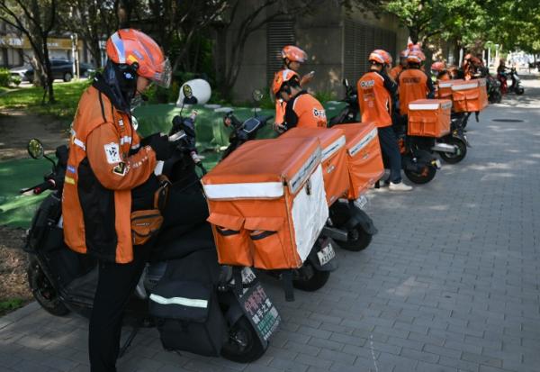 Des livreurs de repas attendent des commandes au bord d'une rue à Pékin, le 2 septembre 2026