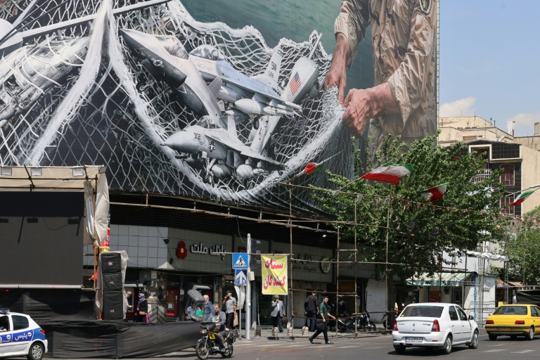 Des véhicules passent devant un immense panneau d'affichage sur lequel est écrit 