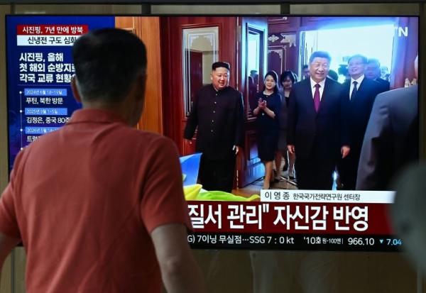 Un homme passe devant un écran de télévision diffusant un journal télévisé avec des images d'archives de la rencontre de 2019 entre le président chinois Xi Jinping et le dirigeant nord-coréen Kim Jong Un, dans une gare de Séoul, le 8 juin 2026
