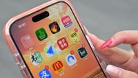 Une utilisatrice de Xiaohongshu se prépare à ouvrir l'application chinoise (en haut à droite) alors qu'elle visite la Cité interdite à Pékin, le 11 juillet 2026