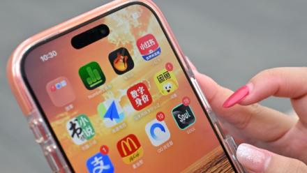 Une utilisatrice de Xiaohongshu se prépare à ouvrir l'application chinoise (en haut à droite) alors qu'elle visite la Cité interdite à Pékin, le 11 juillet 2026